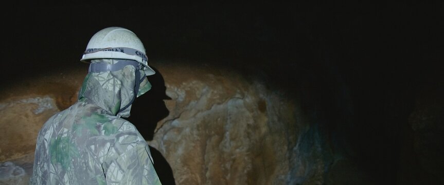 Preservation of earth resources. Scientist exploring of cave for geology science. Engineer check stalactites.Professional speleology worker in helmet carry out visual inspection on underground nature