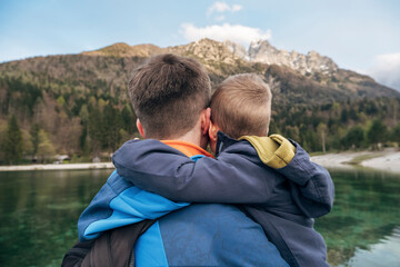 Father and son embracing while enjoying a scenic mountain view by a lake