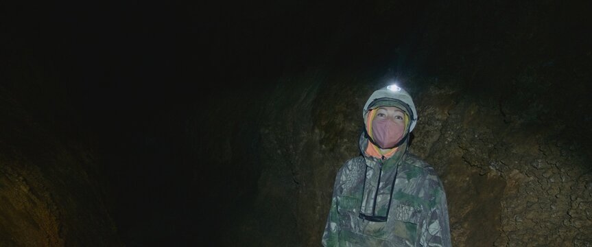 The cave excursion travel experience. The woman tourist marveled at the rock stone formations in the dark cavern. The cave tourism indoor.Its an attraction for adventure and nature lovers on any tour