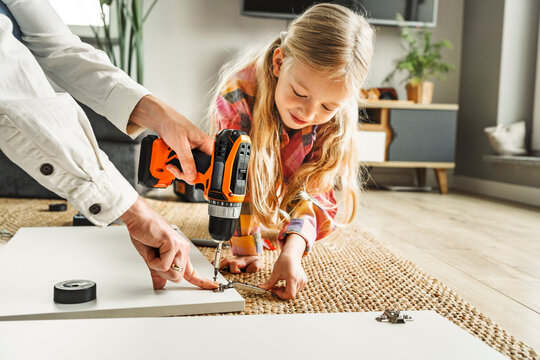 Father and daughter assembling furniture together at home
