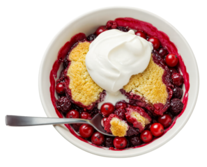 Delicious cranberry fruit cobbler with a dollop of whipped cream and a spoon