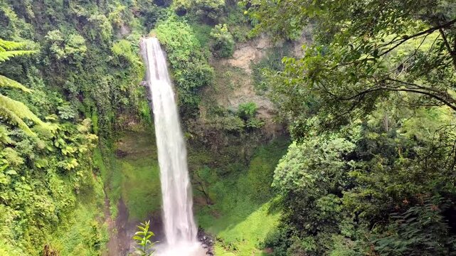Curug Pelangi or Rainbow Waterfall, Bandung, Indonesia, surrounded by green grass.