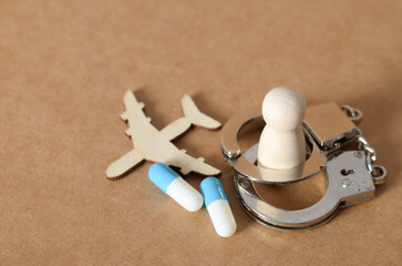 Drug Trafficking Concept with Airplane, Capsules, Handcuffs, and Wooden Figure Representing Arrest
