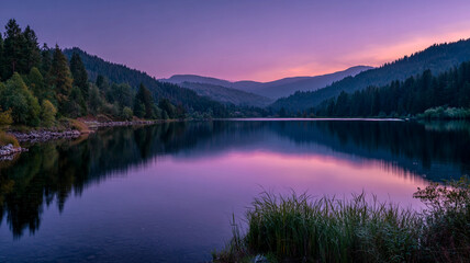 Tranquil mountain lake at dusk reflects serene colors of sunset, surrounded by lush forests and rolling hills. calm water mirrors vibrant sky, creating peaceful atmosphere