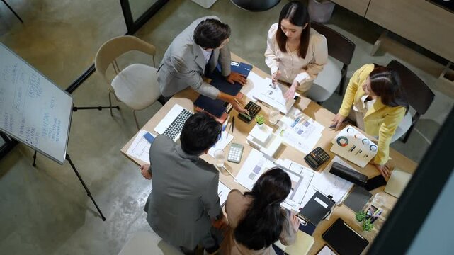 Strategic planning meeting by Asian professionals in stylish home office captured from overhead perspective