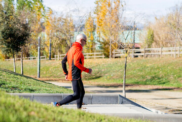 Senior man running up stairs in an outdoor park setting