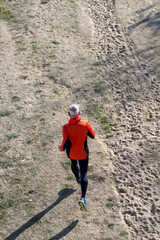 Senior man running on dirt trail from aerial perspective