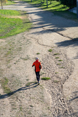 Senior man running on dirt trail from aerial perspective