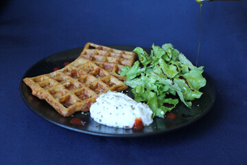 Savory waffles, with ham, grated cheese and grated carrot, served with white cheese, spicy red drops and balsamic green salad.