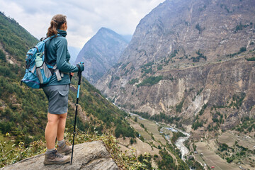 Hiker with backpack against picturesque mountain valley during Manaslu Circuit trek in Himalayas, Nepal.