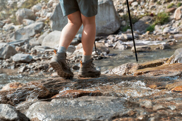 Hiking shoes on hiker walking crossing mountain creek. Woman on hike trekking in nature.