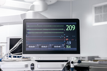 View on medical vital signs monitor in sterile white operating room in a hospital. Health care device displays heart rate, oxygen levels, pressure indicators. Medical equipment. High quality photo