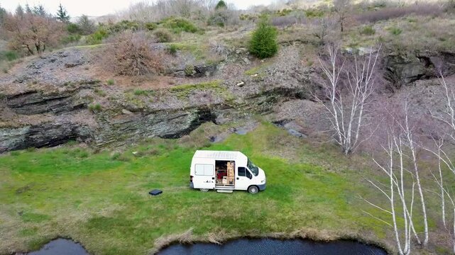Vanlife en fourgon am&eacute;nag&eacute; au bord d'un &eacute;tang vue drone