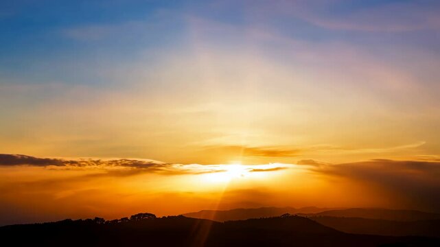 Golden sun dips below the mountain horizon, painting the evening sky with beautiful orange and red light