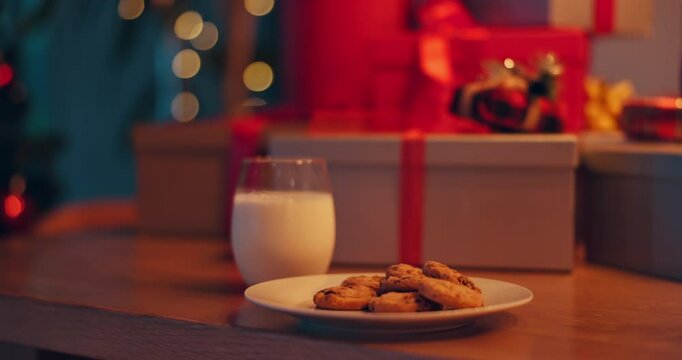 Gifts, milk and cookies on table for Christmas eve with celebration, tradition or holiday season. Presents, sweet treat and biscuits with dairy drink for festive dessert for Santa Claus in home.