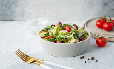 Vegetarian salad with lettuce, tomatoes, croutons, olives and parmesan cheese in a bowl
