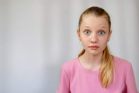 Surprised Girl With Shocked Facial Expression. Young girl with wide eyes and raised eyebrows showing a surprised or shocked expression, isolated on light background for emotion concept. copy space.