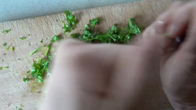 Hirtshals,Denmark A pair of hands chops parsley on a wooden board.