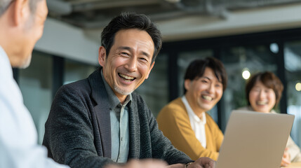 group of people in a meeting, smiling. They seem to be enjoying themselves and the collaborative environment. They look happy and engaged in their discussion