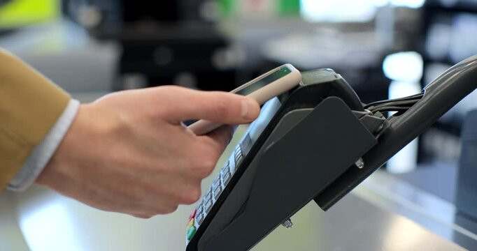 Closeup man paying with smartphone at the checkout counter in the supermarket. Payment scanning nfc technology contactless payment wireless device concept.