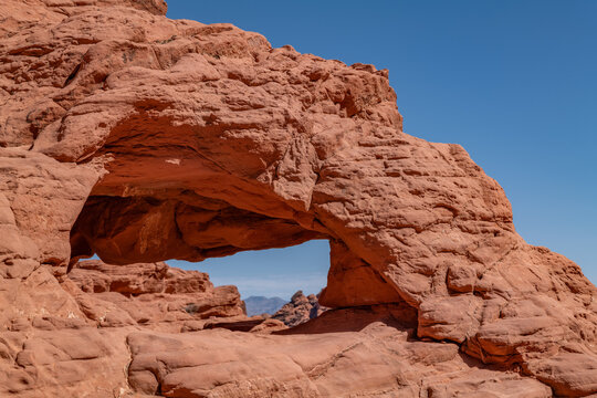 A small natural arch / natural bridge, red Aztec Sandstone outcrops. Rainbow Vista Trail, Valley of Fire State Park, Clark County, Nevada geology. Weathering joints - Powered by Adobe