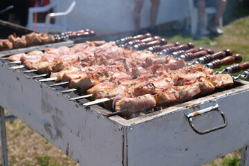 Pork shashlik is fried on a grill on a summer day. Meat is fried on skewers. Cooking meat on coals, street food at a city fair