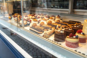 Glass display of a French patisserie showcasing various gourmet pastries including eclairs, tarts