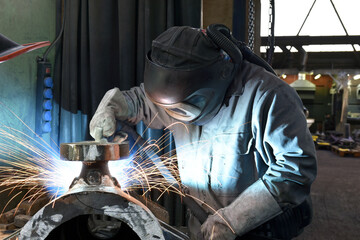 Welder in protective clothing at the workplace in an industrial company in steel construction