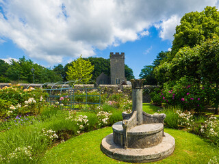 Rosery at St Fagans with an ornate stone bench and the medieval tower of St Mary's Church behind (Cardiff, Wales, United Kingdom)