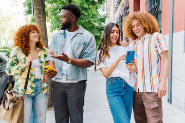 Young friends walking together in urban environment, using smartphones for navigation, connecting,...