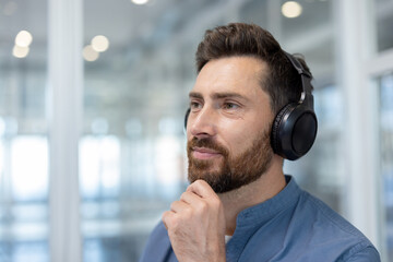 A pensive man wearing headphones, gazing into the distance, lost in thought. Soft lighting and...