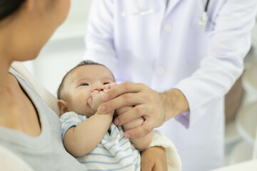 Obraz premium The doctor examines the baby by holding and moving the baby in various positions, checking the baby's cries, and using a stethoscope to check the baby's internal symptoms.