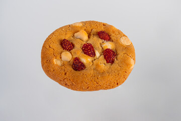 Vanilla cookies topped with nuts and strawberries on a white background
