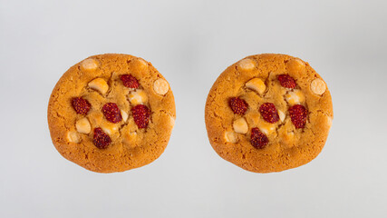 Vanilla cookies topped with nuts and strawberries on a white background