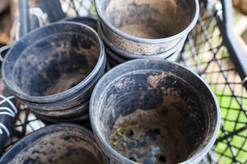 A pile of dirty black plant pots, stacked on top of each other. Some pots contain remnants of soil or debris. Perfect for gardening, repotting, or seasonal cleanup.
