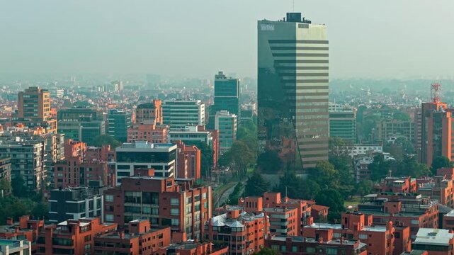 Ascending aerial view with contrasts of modern architecture and clay brick buildings, Bogota Colombia with pollution in the air.