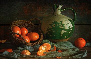 Still life with an old ceramic jug and tasty and ripe tangerines.