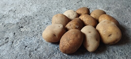 A rustic arrangement of freshly harvested organic potatoes, whole raw vegetables piled on a...