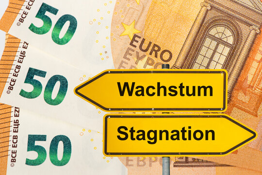 Zwei Wegweiser zeigen in unterschiedliche Richtungen und sind beschriftet mit dem Aufdruck Wachstum vs. Stagnation vor Euro Banknoten - FOTOMONTAGE