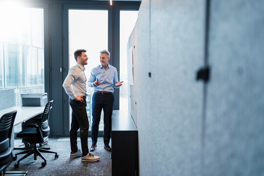 Mature businessman gesturing while talking with male colleague in office