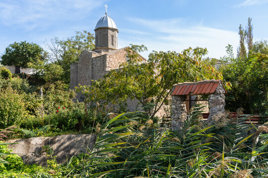 Orthodox Church - Church of Iberian Mother of God or Armenian Church - Church of John Baptist, is located among lush greenery. Dome of church with cross is against backdrop of clear blue skies.