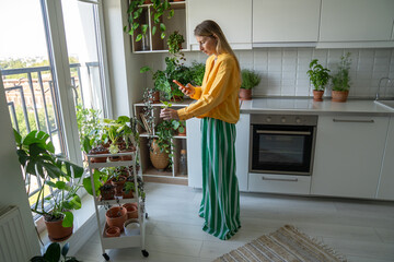 Woman blogger filming phone vlog about botany holding small potted Scindapsus, sharing plant care...