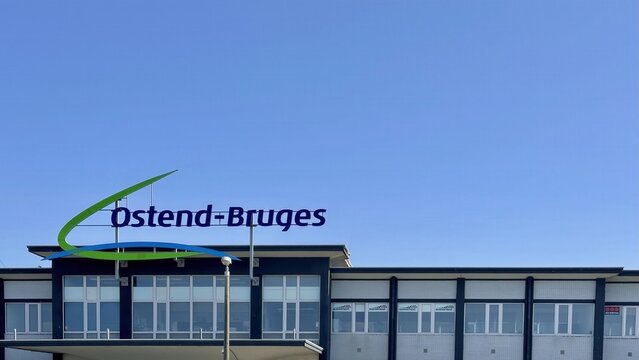 Facade of Ostend-Bruges Airport building in Belgium with bold logo and bright blue sky on a sunny day, Oostende, Belgium, June 3th, 2025