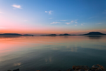Colorful sunset over calm lake and hills
