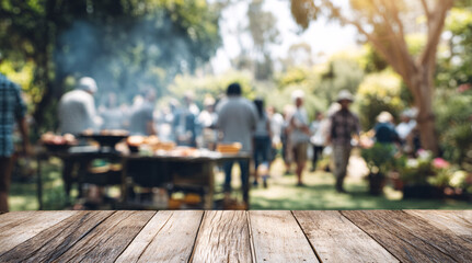 Wooden table surface with blurred outdoor barbecue party background and people gathering. Empty deck space for product display against social dining setting