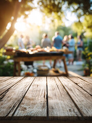 Wooden table surface with blurred outdoor barbecue party background and people gathering. Empty deck space for product display against social dining setting