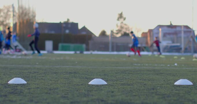 Dedicated soccer players are practicing drills on a large field filled with training cones