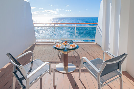 Petit d&eacute;jeuner sur la terrasse d'une cabine balcon d'un navire de croisi&egrave;re avec vue dans le sillage du bateau. 