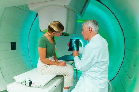 Doctor consulting with patient in a radiology room examining spine x-ray