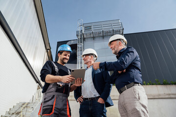 Engineers discussing a project outdoors with a tablet